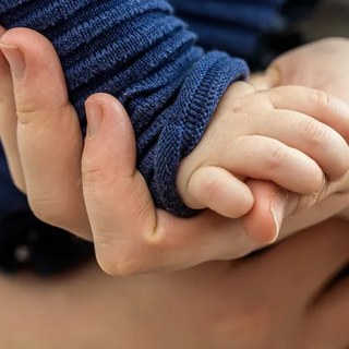 Dłoń dorosłego podtrzymująca dłoń dziecka